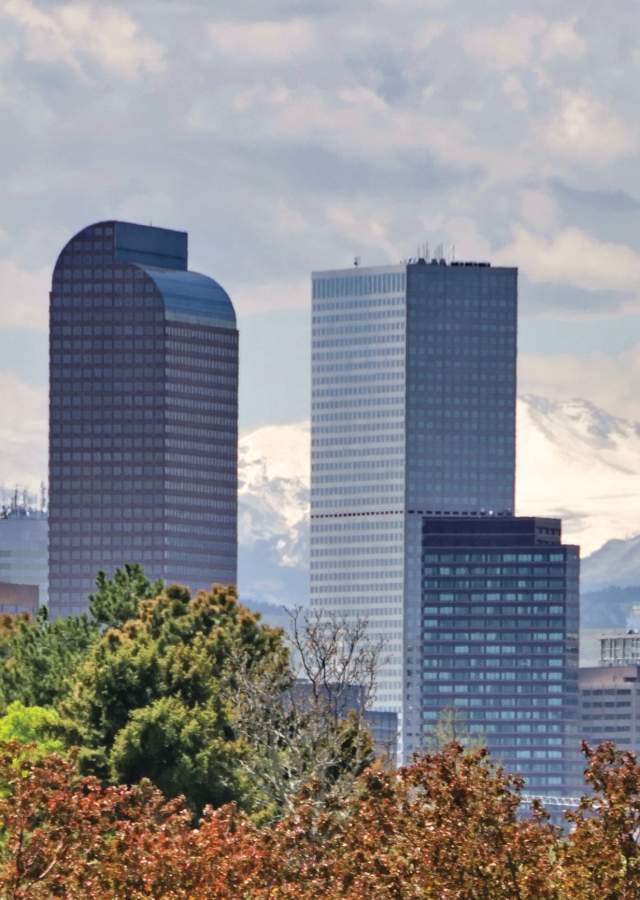 Golfers at City Park with Denver skyline and mountains.